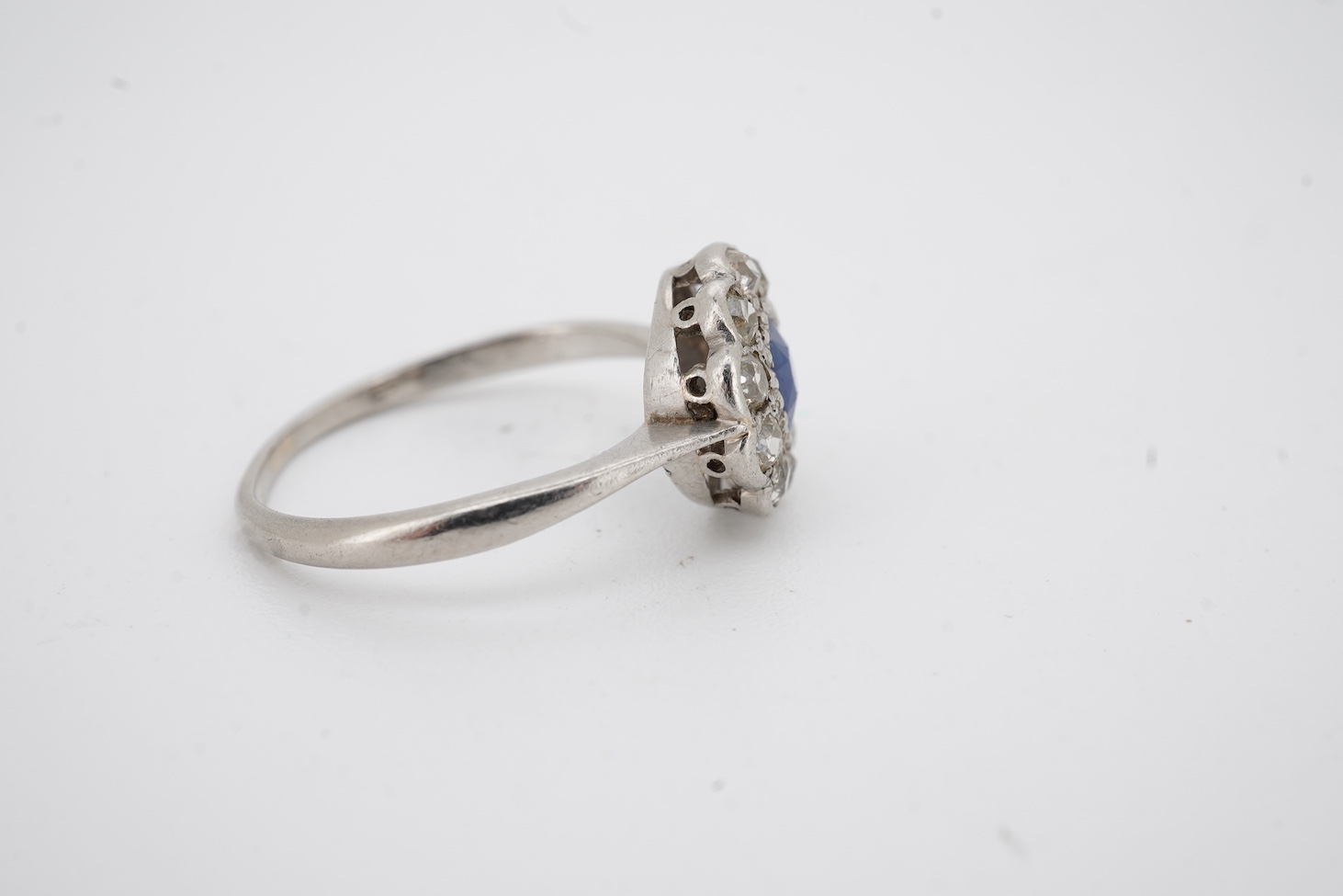 A 1920's white metal(stamped plat), sapphire and diamond set circular flower head cluster ring, size J, gross weight 2.7 grams.
